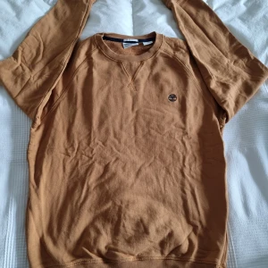 Brun tröja från Timberland - Säljer en snygg brun tröja från Timberland i herr storlek M. Tröjan har en klassisk rund hals och är i mycket bra skick. Perfekt för höst och vinter med sitt mjuka material och stilrena design. Timberlands logga är broderad på bröstet. Passar både till vardags och lite mer uppklädda tillfällen.