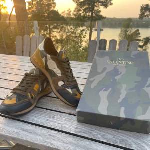 Säljer ett par snygga Valentino Rockrunner sneakers i camouflage. De har en cool mix av färger som grön, brun och gul med mockadetaljer. Skorna är i mycket bra skick och kommer med originalkartong. Perfekta för hösten och våren!