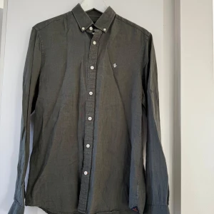 Olivgrön linneskjorta från Morris - Säljer en stilren olivgrön skjorta från Morris i 100% linne. Perfekt för både vardag och fest! Skjortan har långa ärmar och knappar framtill. Den är i bra skick och passar perfekt till höst- och vårgarderoben. En klassiker som aldrig går ur tiden!