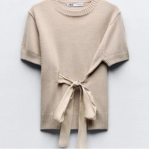 Beige stickad topp från ZARA - Säljer en superfin beige stickad topp från ZARA. Den har korta ärmar och en snygg knytning i midjan som ger en extra touch. Perfekt till vintern!❄️❤️