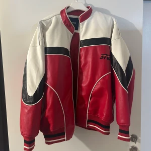  Motorbike jacka från Pull&Bear!  - Säljer en snygg röd och vit jacka från Pull&Bear med coola svarta detaljer och texten 'AUTOMOTIVE Engineering' på ryggen. Jackan har en dragkedja framtill och ribbade muddar vid ärmslut och nederkant. Perfekt för en sportig look eller en utekväll! För både kvinnor & män, en helt ny jacka oanvänd. Sälj även inte längre i butik. 