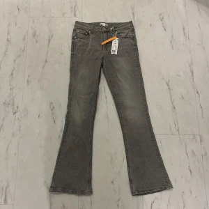 Grå bootcut jeans från Gina Tricot - Säljer ett par snygga grå bootcut jeans från Gina Tricot i storlek 164. Helt oanvända med prislapp kvar, byxorna är från gina young avdelningen, skulle kalla dem mid waist men kan oxå ses som low!