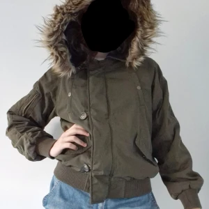 Y2K bomberjacka - Supersnygg bomberjacka från Primark 🎀 Sparsamt använd, inga defekter! Khakifärgad med brun pälsluva och markerad midja.  Storlek XS på lappen men passar S-M! Fejkfickor framtill på jackan och en riktig på ena ärmen.  Stängs med dragkedja och knappar.