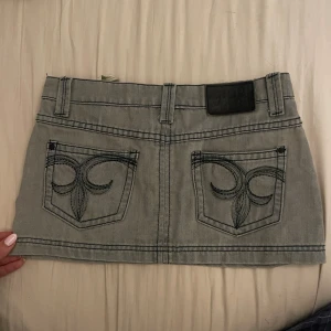 Grå jeanskjol från Crop Girl - Säljer en supercool lågmidjad jeanskjol från Crop Girl. Den har snygga broderade detaljer på bakfickorna som gör den unik. Perfekt för en avslappnad look eller en utekväll. Passar perfekt till vår och sommar! Kjolen är i toppen skick utan några somhelst defekter!🩷🩷midjemått:37