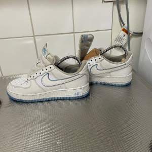 Säljer ett par klassiska Nike Air Force i vitt med blå detaljer. Skorna har en snygg blå sula och är i bra skick med lite slitage. Perfekta för vardagsbruk eller en avslappnad stil. Priset ej hugget i sten, hör av er vid funderingar .