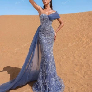 Blå glittrig långklänning - Säljer en fantastisk blå långklänning med glittriga detaljer och en elegant släp. Klänningen är axelbandslös och har en tight passform som framhäver figuren. Perfekt för bal eller fest! ✨