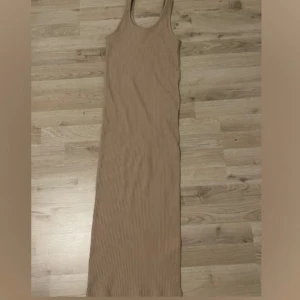 KLÄNNING  - En beige klänning i storlek S, Använd fåtal gånger. Den har en skön linne material . Är 1,65 och klänningen når ända till fötterna.