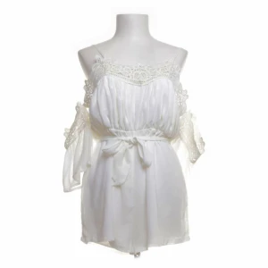 Playsuit med Spets - • Normal - Bred passform • Upplevs som storlek 34-38 • Bild 4 och 5 visar färgen bäst (helt vit) • Tunnt och luftigt tyg med ett mjukt undertyg så att man inte ser igenom • Dragkedja i ryggen