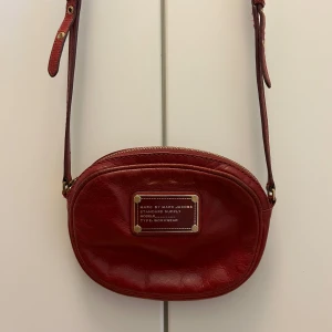 Vinröd marc jacobs  - Vinröd cross-body Marc jacobs i läder. Använd men inget trasigt. Justerbart band. Mått: 13x17x2 cm