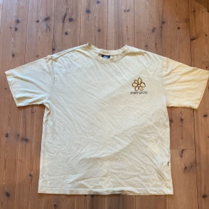 Gul t-shirt från SWEET SKTBS - Säljer en snygg gul t-shirt från SWEET SKTBS i storlek small passar som M. Den har en cool blomma och texten 'SWEET SKTBS' tryckt på framsidan. Perfekt för en avslappnad stil och gjord i mjukt bomullsmaterial. Passar perfekt till sommaren!