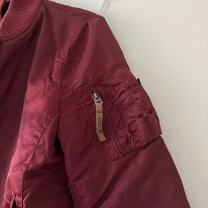 Vinröd jacka  - Bomberjacka från Alpha Industries. Passar snyggast på en S 
