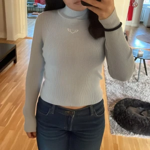 Ljusblå ribbad polotröja från H&M Divided - Säljer en superfin ljusblå ribbad polotröja från H&M Divided. Den har en söt broderad detalj med ett hjärta med vingar på bröstet. Perfekt för kyliga dagar då den är väldigt värmande. Tröjan är i mycket bra skick då den endast använts 1 gång 🌟