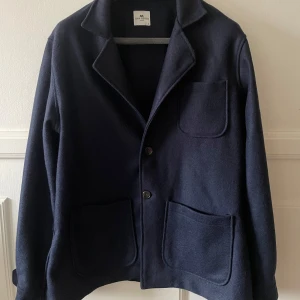 Mörkblå kavaj från Universal Works - Säljer en stilren mörkblå kavaj från John Henric. I fint skick