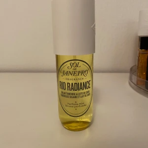 Sol de Janeiro Rio Radiance Parfym - Säljer en fräsch och exotisk doft från Sol de Janeiro, Rio Radiance. Flaskan är genomskinlig med en gul vätska och har en stilren vit kork. Perfekt för dig som älskar tropiska och somriga dofter med inslag av tuberos och kokosmjölk. Perfekt att ha med sig i väskan för en snabb uppfräschning!
