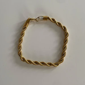 Guldarmband med tvinnad design - Snyggt guldarmband med en elegant tvinnad design. Perfekt för att ge en touch av lyx till vilken outfit som helst. Armbandet har en säker låsning och är i mycket bra skick. Passar både till vardags och festliga tillfällen.