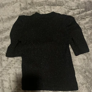 Svart glittrig tröja från Lindex - Säljer en snygg svart tröja från Lindex med glittrigt material. Perfekt för festliga tillfällen! Tröjan har trekvartsärmar och en normal passform. Den är i mycket bra skick och redo för att användas på nästa party. ✨Tvättas självklart innan den skickas💓Kontakta mig och så kan jag skicka fler bilder och svara på frågor!🥰