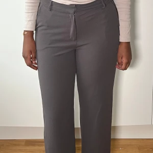 Grå kostymbyxor -  Byxorna har en hög midja och är gjorda i ett bekvämt material.