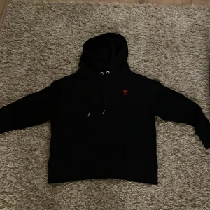 Svart hoodie Ami Paris - Säljer en snygg svart hoodie från Ami. Använd fåtal gånger. Perfekt för både höst och vinter och har en bra passform. Huvan har dragsko för justering. Perfekt för en casual look! 