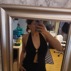 Svart glittrig topp  från H&M - Snygg glittrande topp från H&M i storlek M. Den har en halterneck-design med en ring framtill och en öppen rygg. Perfekt för festliga tillfällen såsom nyår! 🖤