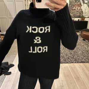 Svart polotröja med text - Säljer en svart polotröja med texten 'ROCK & ROLL' i vitt, från Zadig Voltaire. Tröjan är stickad och har långa ärmar. Sparsamt använd och inga defekter. Står ingen storlek men sitter såhär på mig som är 175.❤️
