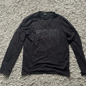 Hugo Boss tröja - En svart Hugo Boss tröja. Den är använd ett fåtal gånger men har väldigt små användnings tecken.
