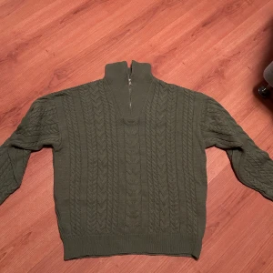 stickad tröja med dragkedja från Asos - Säljer en olivgrön stickad tröja från The New Look i storlek M, köpt från asos. Tröjan har en halv dragkedja och ett snyggt flätmönster på framsidan. Perfekt för höst och vinter, och den är supermysig att ha på sig. Passar både till vardags och lite finare tillfällen. 🧶🍂