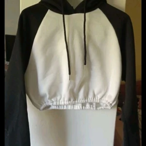 Svartvit croppad hoodie - Säljer en snygg svartvit croppad hoodie med långa ärmar. Perfekt för en avslappnad stil, med justerbara snören i huvan. Den är i bra skick och passar perfekt till både jeans och leggings. Perfekt för höst och vår!