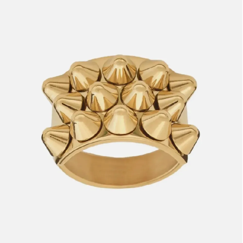 Cool och edgy guldfärgad ring med nitar i ett geometriskt mönster. Perfekt för att ge din outfit en tuff touch. Ringen är i mycket bra skick inga repor . Accessoarer.