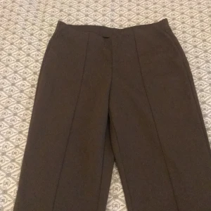 Bruna kostymbyxor från Gina Tricot - Säljer ett par eleganta bruna kostymbyxor från Gina Tricot i storlek XS. Byxorna har en hög midja och en klassisk rak passform som ger en stilren look. Perfekta för både kontoret och festligare tillfällen. 👜✨