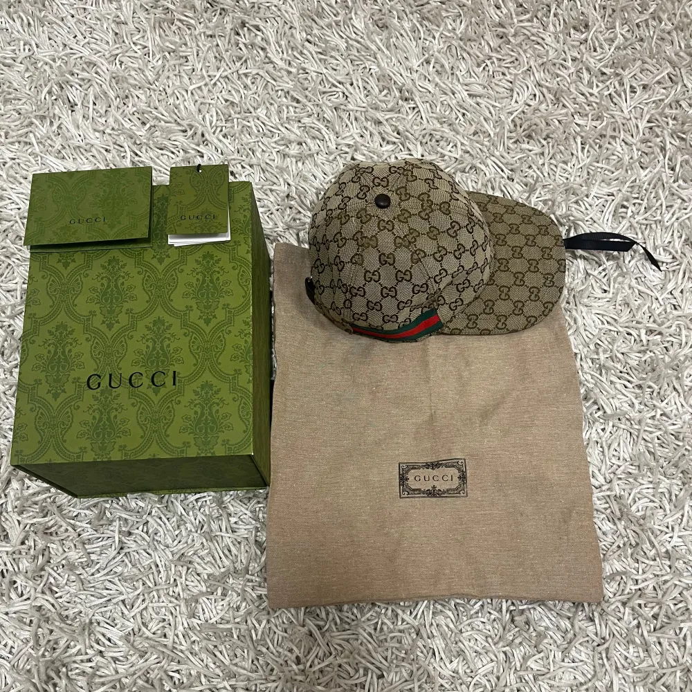 Säljer en snygg beige Gucci keps. Kepsen har en justerbar rem baktill och detaljer i rött och grönt på sidorna. Perfekt för att ge din outfit en lyxig touch. Kommer med originalförpackning och dustbag.. Accessoarer.