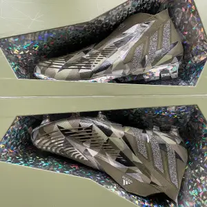 Säljer ett par grymma Adidas Predator fotbollsskor i camouflagemönster. Skorna är i nytt skick och har en cool design med grå och svarta detaljer. Perfekta för fotbollsplanen med sina vassa dobbar och snygga look. Kommer i originalförpackning. Addidas x Swarovski kollektion. Nypris 3200kr