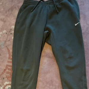 Gröna mjukisbyxor från Nike - Säljer ett par gröna mjukisbyxor från Nike i storlek XL. De är i bra skick och perfekta för träning eller chill. Byxorna har en elastisk midja med snörning för bästa passform och en liten Nike-logga på benet. Superbekväma och stilrena!