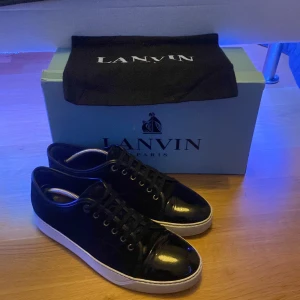 Svarta Lanvins - Säljer ett par snygga svarta sneakers från Lanvin i bra skick. De har en stilren design med svart mocka och vit sula. Dom passar 42/43 UK 8 