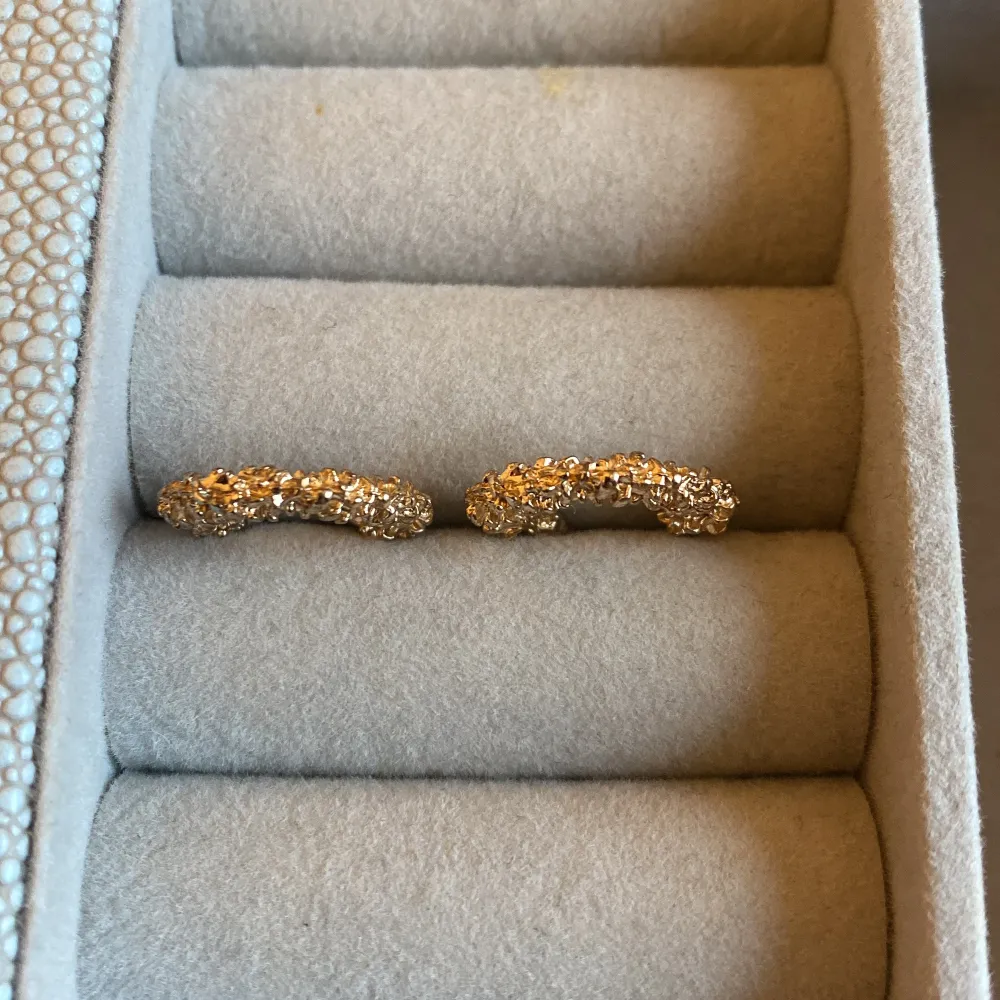 Säljer ett par fantastiska guldglittriga örhängen i form av halvcirklar. De är täckta med små glittrande detaljer som ger en lyxig känsla. Perfekta för att lysa upp vilken outfit som helst, oavsett om det är till fest eller vardag. Passar perfekt för jul och nyår!. Asusteet.