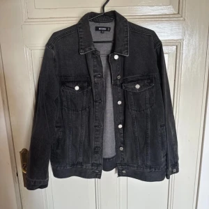 Svart jeansjacka  - Säljer en snygg svart jeansjacka från Bershka i bra skick. Den har en klassisk design med knappar framtill och två bröstfickor med lock. Perfekt för höst och vår, och funkar till nästan alla outfits. Storleken är dam S. Passa på att uppgradera din garderob med denna stiliga jacka!
