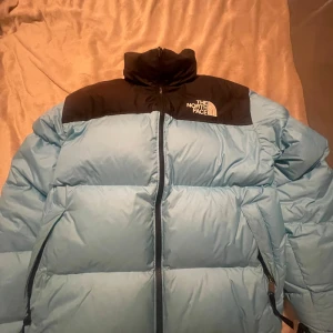 Blå pufferjacka från The North Face - Säljer en snygg och varm blå retro pufferjacka från The North Face.. Perfekt för kalla vinterdagar. Den är i mycket bra skick!.