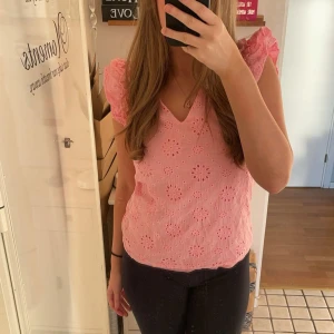 Rosa blus med volangärmar - Säljer en söt rosa blus med v-ringning och volangdetaljer på ärmarna. Blusen har ett blommigt mönster och är perfekt för vår och sommar. Den är i mycket bra skick och passar både till vardags och fest.