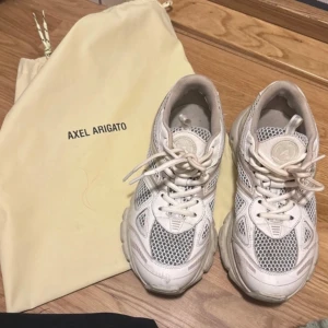 Vita sneakers från Axel Arigato - Säljer ett par vita sneakers från Axel Arigato i mycket bra skick. De har en snygg och modern design med snörning. Perfekta för både vardag och fest! Nypris 3500