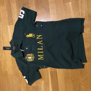 Cheif Keef Ralph Lauren polo - Snygg grön pikétröja från Ralph Lauren med texten 'MILAN' och en stor gul logga på framsidan. Tröjan har korta ärmar med siffran '5' tryckt på båda ärmarna och ryggen. Perfekt för en sportig look! Skick 9.5/10 helt oanvänd kom dm om frågor 