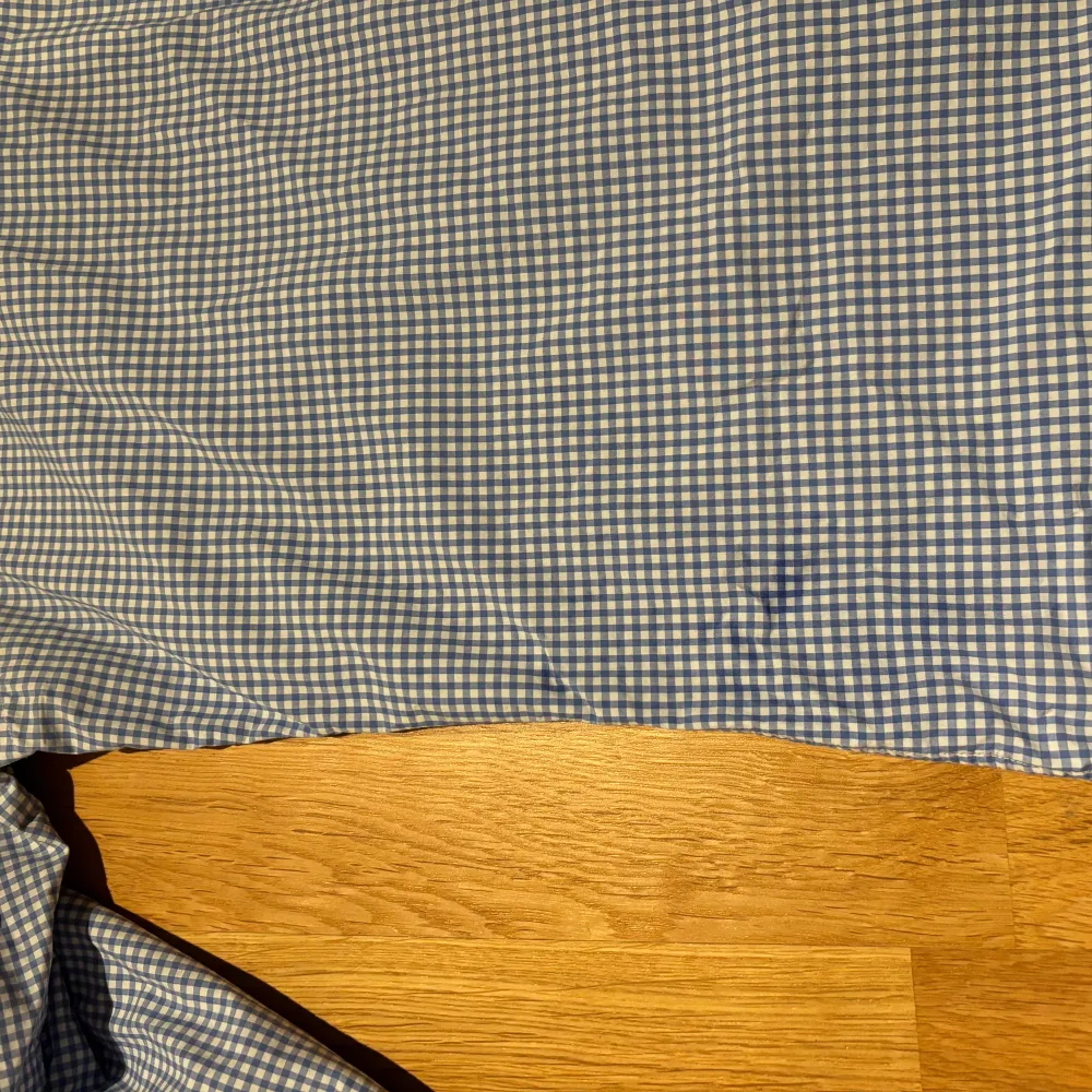 Säljer en klassisk rutig skjorta från Polo Ralph Lauren i blått och vitt. Skjortan har långa ärmar och knappar framtill. Den är tillverkad i bomull och har en broderad logotyp i rosa på bröstet. Perfekt för en stilren look! Har små blåa fläckar nere på sidan.. Paidat.