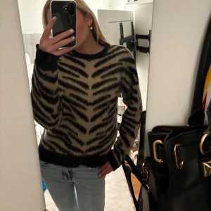 Zebramönstrad tröja i beige och svart - Säljer en snygg zebramönstrad tröja i beige och svart. Tröjan har långa ärmar och en normal passform, perfekt för att ge din outfit en trendig touch. Passar bra till jeans eller kjol för en avslappnad look.