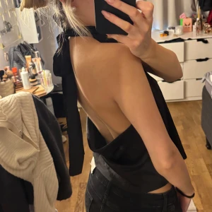 Svart halterneck topp - Snygg svart halterneck topp med öppen rygg och knytband i nacken. Perfekt för fest!!