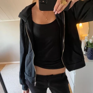 Svart hoodie med dragkedja - Säljer en svart hoodie med dragkedja och huva. Den har långa ärmar och en bekväm passform. Perfekt för en avslappnad stil.