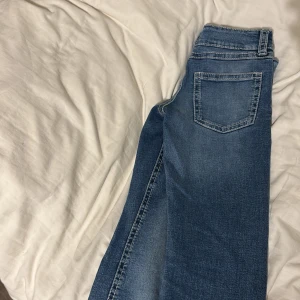 Blå jeans från Gina Tricot - Snygga blå jeans från Gina Tricot med klassisk femficksdesign och dubbla knappar i midjan. Perfekta för en avslappnad stil. De har en rak passform och är tillverkade i ett bekvämt denimtyg.