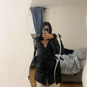 Svart parkajacka från Parajumpers - Säljer en svart parkajacka från Parajumpers med en mysig pälsfodrad huva. Jackan har en slim fit passform och är perfekt för vintern. Den har en snygg orange detalj vid halsen och flera praktiska fickor. Perfekt för kalla dagar! ❄️ och vill du se mer av jackan är det bara att skriva! 