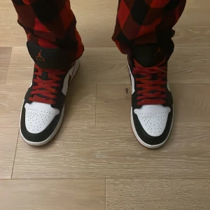 Nike Air Jordans1 i svart, vitt och rött - Säljer ett par Nike Air Jordans i klassisk svart, vit och röd färgkombination. Skorna har röda snören och en hög design. Små märken har o där ksk går att ta bort vet int. Har du frågor tveka int att fråga🤝 (kan gå med på att sänka priset)