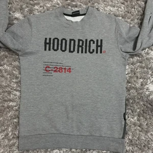 Grå sweatshirt från Hoodrich - Säljer en grå sweatshirt från Hoodrich med tryck fram och bak. Tröjan har en världskarta i rött på baksidan och textdetaljer. Den har långa ärmar och en dragkedja på sidan. Perfekt för en avslappnad stil. Köpte den för 800 kr och tycker det är rimligt att jag säljer den för 550 kr