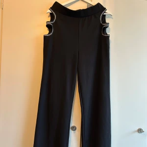 Vida kostymbyxor med hål på höfterna - Snygga kostymbyxor med två hål på höfterna för en lite extra festlig look. Byxor som man verkligen lägger märke till! De är sköna och stretchiga med vida ben. Ingen gylf eller liknande, bara resår. Skriv om du vill ha mer info eller fler bilder! ✨