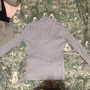 Ljuslila ribbad polotröja från Gina Tricot - Säljer en stilren ljuslila polotröja från Gina Tricot. Tröjan är ribbad och har långa ärmar, perfekt för en elegant look. Den är i storlek S och passar utmärkt för kyligare dagar.