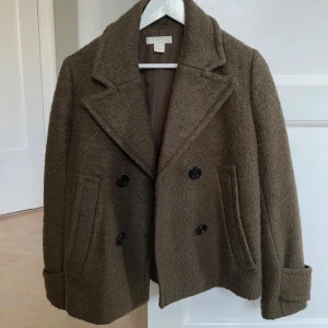 Khaki/brun kappa woolblend - Snygg oliv/khaki/brun kappa med dubbelknäppning! Stl 38 men passar 36 bra också. I 46% ull så varm!